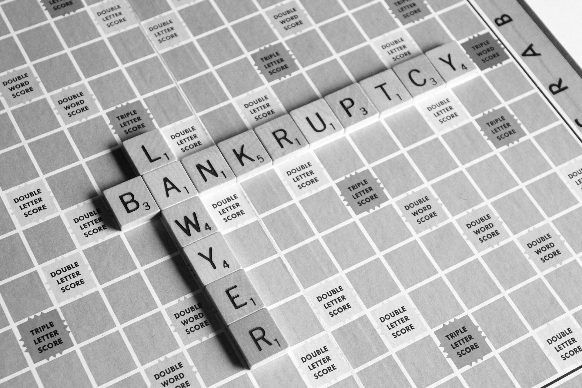 Black and white Scrabble game board with the words 'BANKRUPTCY' and 'LAWYER' formed using letter tiles. ''Bankruptcy Laws''
