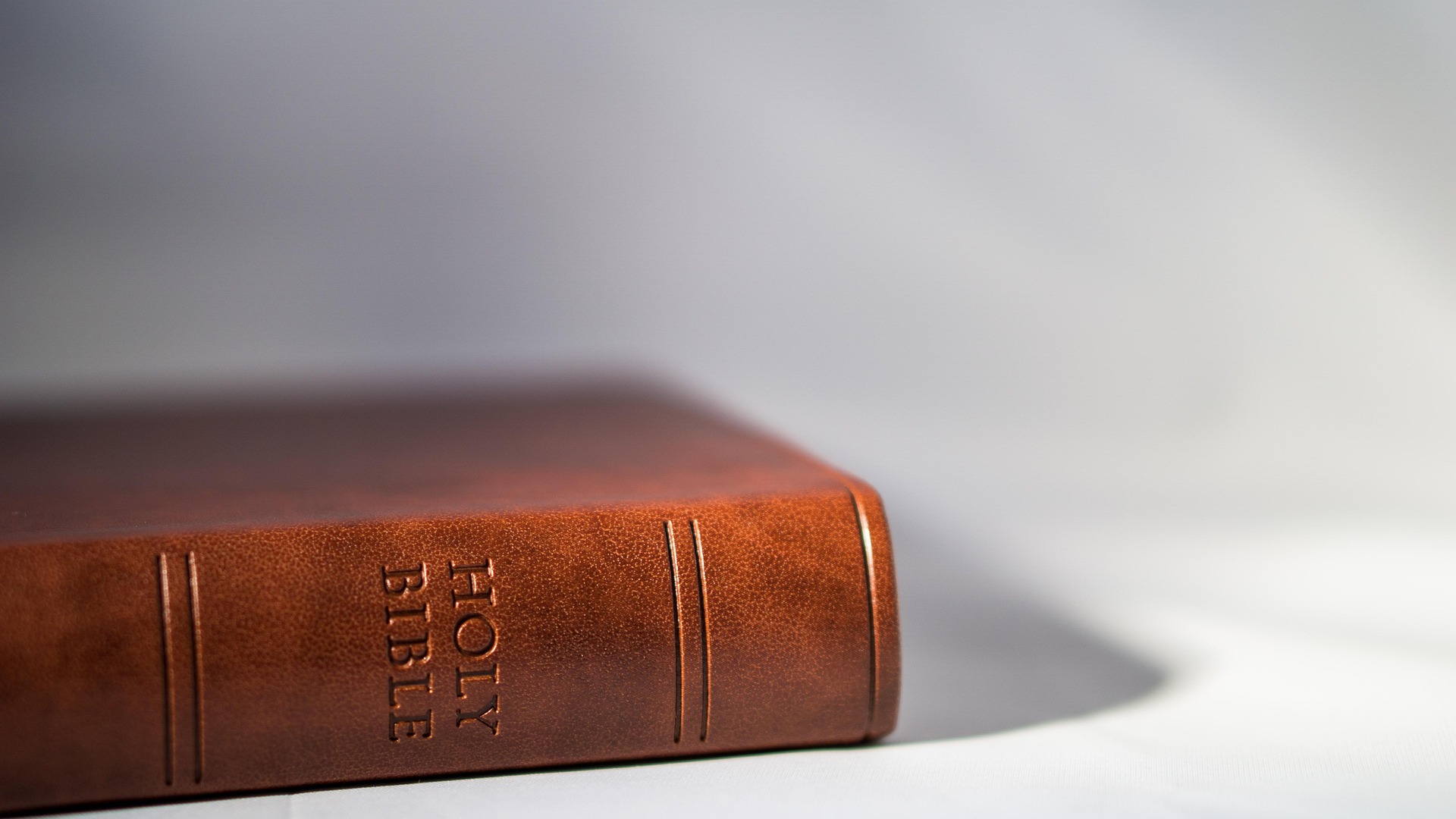 A leather-bound Holy Bible resting on a white surface, symbolizing the foundation for learning how to study the Bible with purpose and faith.