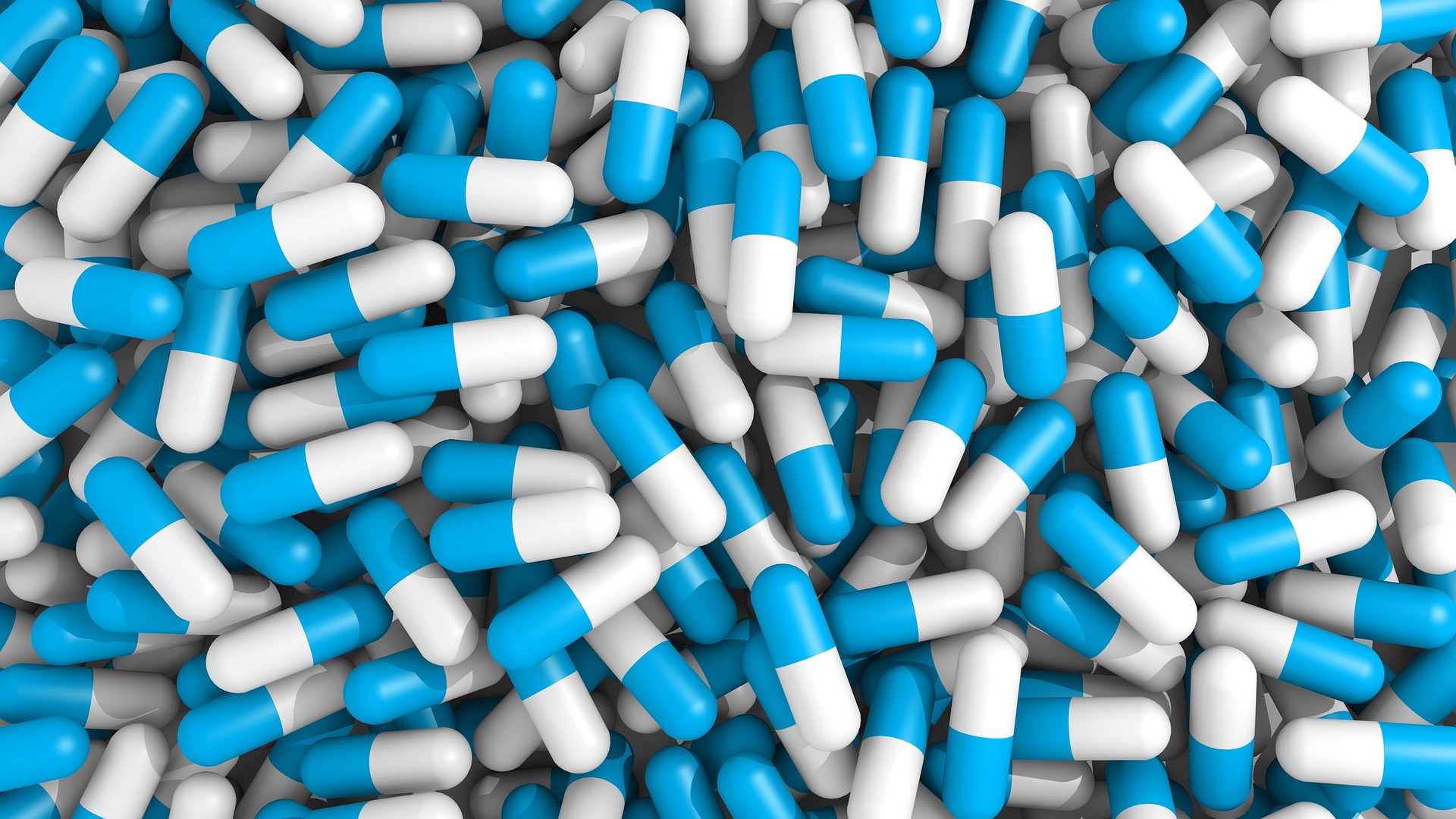 A large pile of blue and white capsules representing blue drugs, highlighting the issue of prescription drug misuse and opioid addiction.